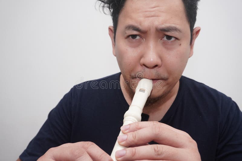 Asiatischer Mann spielt Blockflöte, Musikinstrument lizenzfreie stockbilder