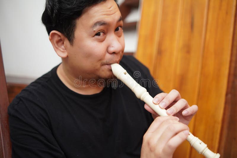 Asiatischer Mann spielt Blockflöte, ein Musikinstrument stockfotografie