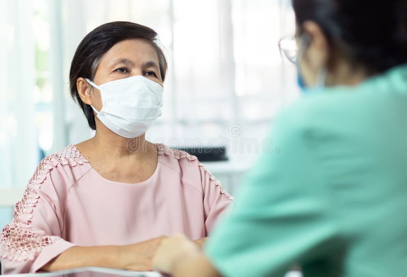 Asiatischer Senior Frauenpatient, der die Schutzwirkung Unterhaltungsberatung der Gesichtsmaske mit Ärztin oder Ihrer Diabetesbera lizenzfreie stockbilder