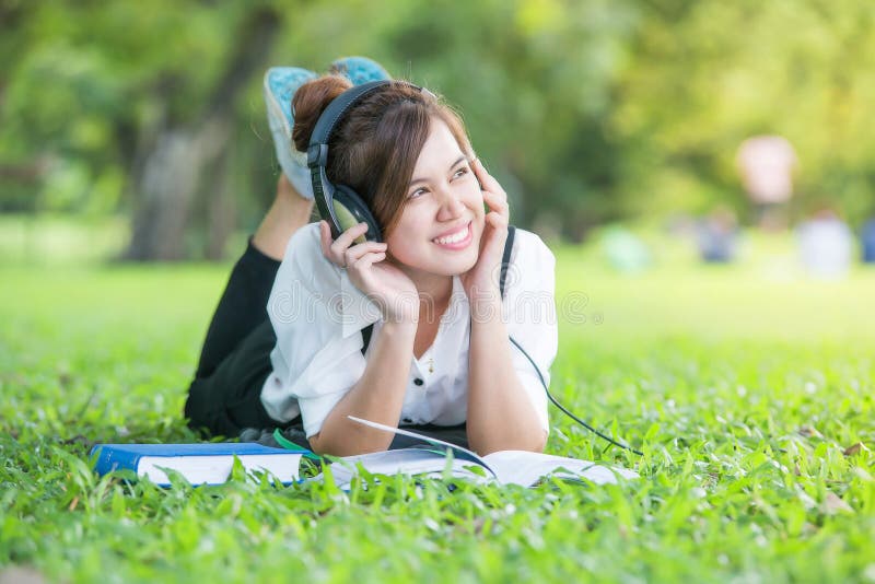 Asian student with Headphones Outdoors. Enjoying Music. Asian student with Headphones Outdoors. Enjoying Music.