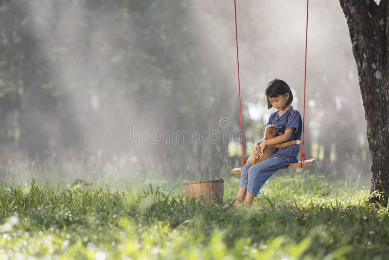 Asiatisches Baby auf Schwingen mit Welpen stockfotografie Asiatisches Baby auf Schwingen mit Welpen stockfotografie