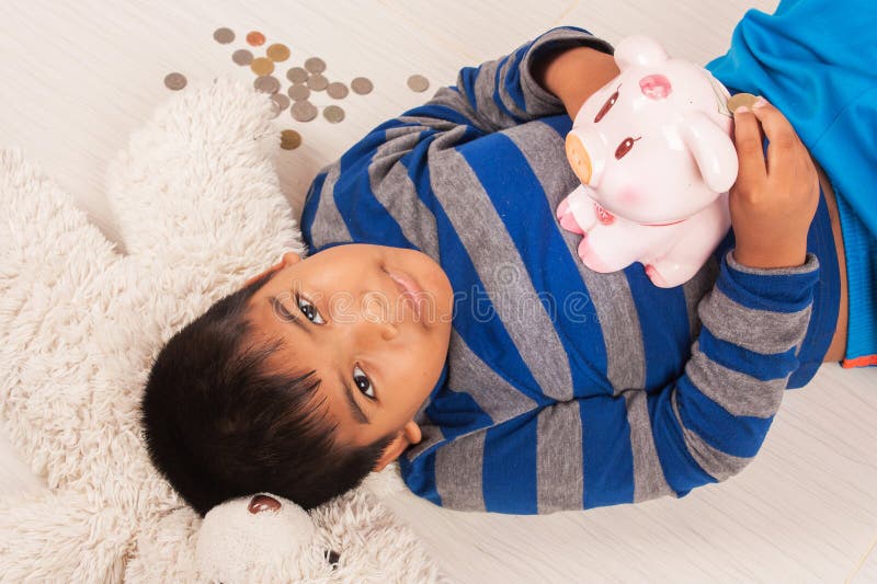Asiatisches Jungeneinsparungsgeld im piggybank stockfoto Asiatisches Jungeneinsparungsgeld im piggybank stockfoto