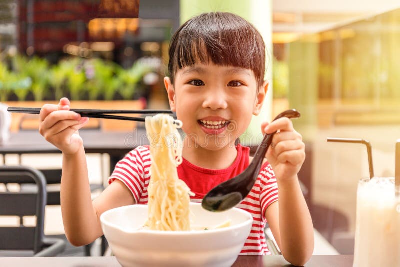Asiatisches kleines chinesisches Mädchen, das Nudelsuppe isst