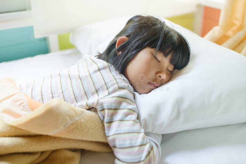 Asiatisches Mädchen, das auf dem Bett bedeckt mit Decke schläft stockfotos Asiatisches Mädchen, das auf dem Bett bedeckt mit Decke schläft stockfotos
