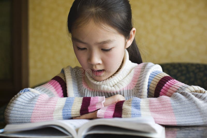 En asiatisk flicka läser en bok royaltyfria foton