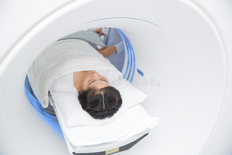 Asian lady sleep on a CT Scan bed and panel control by Radiologic technician. Asian lady sleep on a CT Scan bed and panel control by Radiologic technician