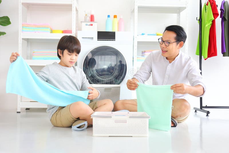 Asian father and  son help each other doing laundry together for daily routine chores. Asian father and  son help each other doing laundry together for daily routine chores