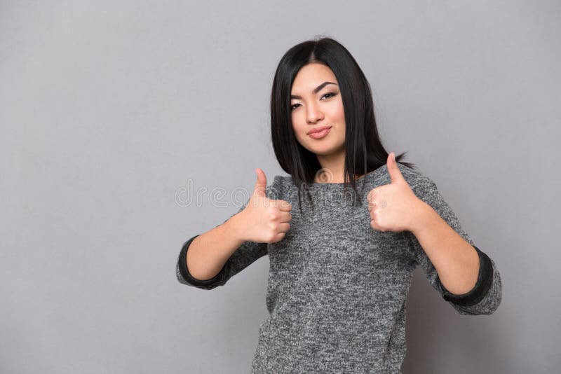 Asiatisk flicka som ger tummar-upp fotografering för bildbyråer