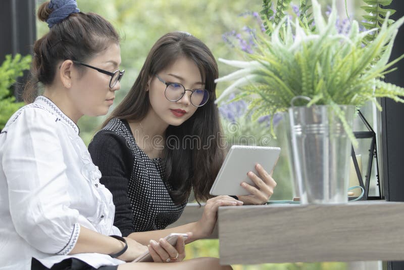 Asiatisk funktionsduglig kvinna som två ser till datorminnestavlaskärmen med s royaltyfria bilder Asiatisk funktionsduglig kvinna som två ser till datorminnestavlaskärmen med s royaltyfria bilder
