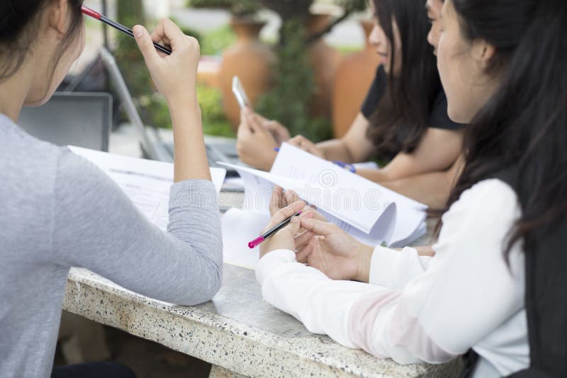 Asiatisk grupp av studenter som använder minnestavlan och anteckningsboken som delar med t royaltyfria bilder Asiatisk grupp av studenter som använder minnestavlan och anteckningsboken som delar med t royaltyfria bilder