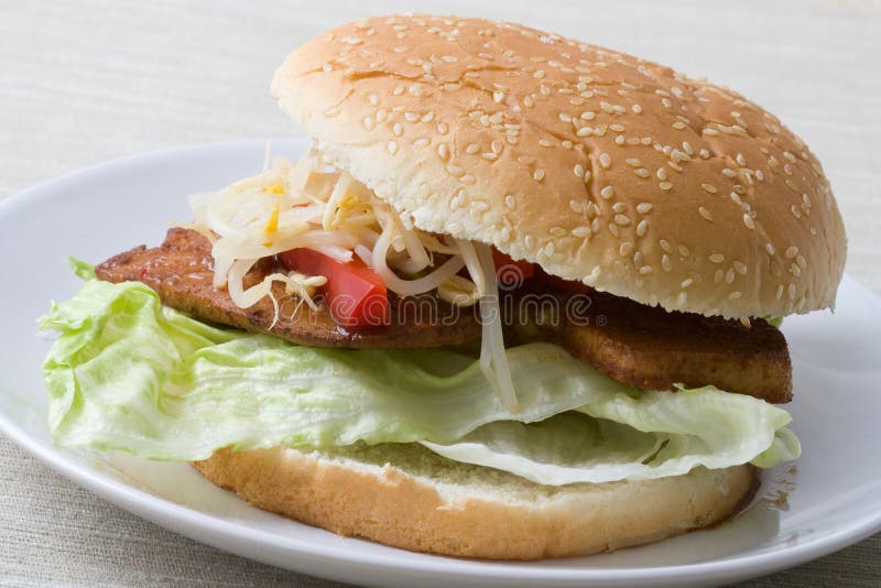 Close-up of an Asian fast food burger made from sprouts, red bell pepper, marinated tofu and iceberg lettuce with seseame bread. Close-up of an Asian fast food burger made from sprouts, red bell pepper, marinated tofu and iceberg lettuce with seseame bread.