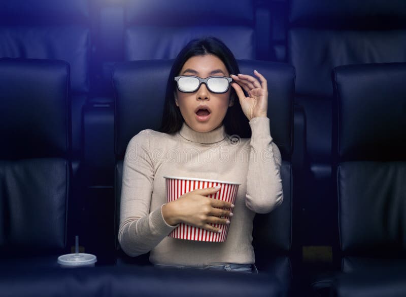 Asiatisk kvinna i 3d-glasögon som tittar på skräckfilmen på bio