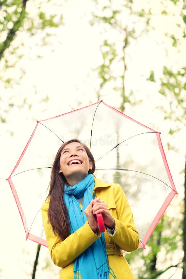 Asiatisk kvinna i hösten som är lycklig med paraplyet i regn
