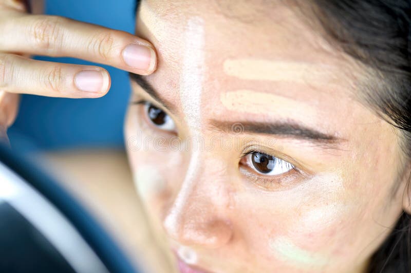Asiatisk kvinna som applicerar makeup, skönhetsmedelfundament genom att använda till att korrigera eller att dölja ansikts- hudpr royaltyfria foton Asiatisk kvinna som applicerar makeup, skönhetsmedelfundament genom att använda till att korrigera eller att dölja ansikts- hudpr royaltyfria foton