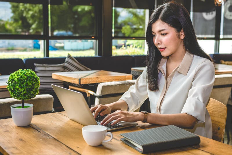 Asiatisk kvinna som arbetar med b? rbara datorn i coffee shop. Folk och livsstilbegrepp. Tema för arbete och arbete samt frilansfr arkivfoto
