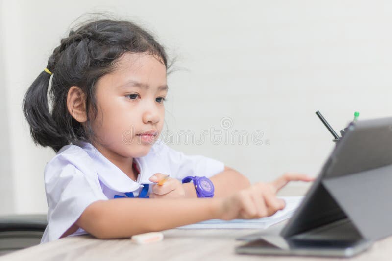 Asiatisk liten flicka i enhetlig görande läxa för student och användata fotografering för bildbyråer