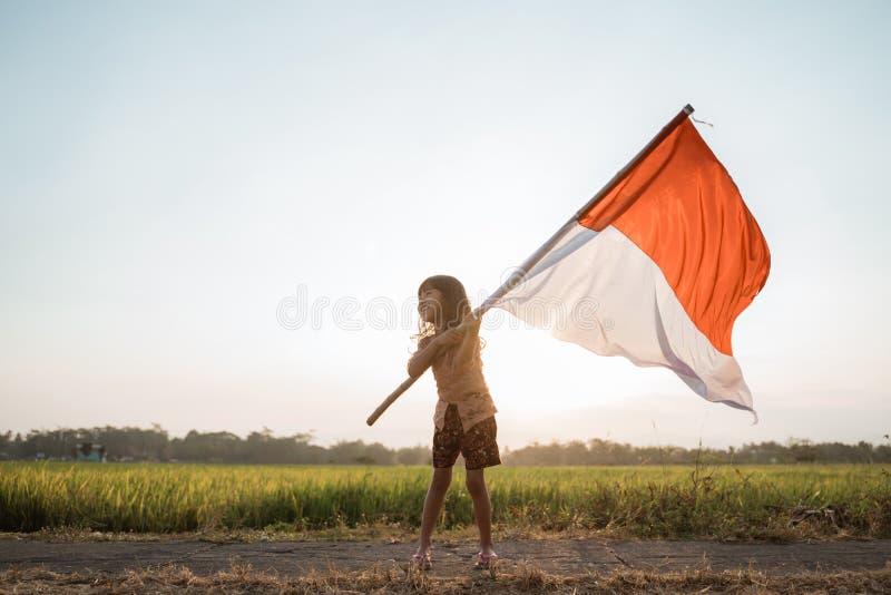 Asiatisk liten flicka som viftar med den indonesiska flaggan arkivfoto