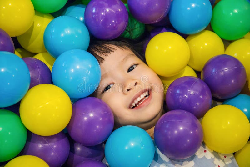 Asiatisk liten kinesisk flicka som spelar med färgrika plast- bollar arkivbilder Asiatisk liten kinesisk flicka som spelar med färgrika plast- bollar arkivbilder