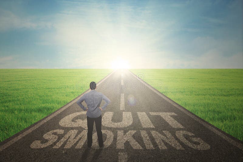 Back view of Asian man wearing casual clothes while standing with a quit smoking word on the road. Back view of Asian man wearing casual clothes while standing with a quit smoking word on the road