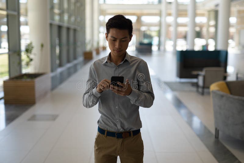 Asiatisk manlig ledare som använder mobiltelefonen i modernt kontor arkivbild Asiatisk manlig ledare som använder mobiltelefonen i modernt kontor arkivbild