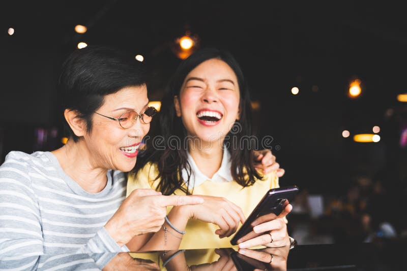 Asiatisk moder och dotter som skrattar och ler på ett selfie- eller fotoalbum, genom att använda smartphonen tillsammans på resta arkivbild Asiatisk moder och dotter som skrattar och ler på ett selfie- eller fotoalbum, genom att använda smartphonen tillsammans på resta arkivbild