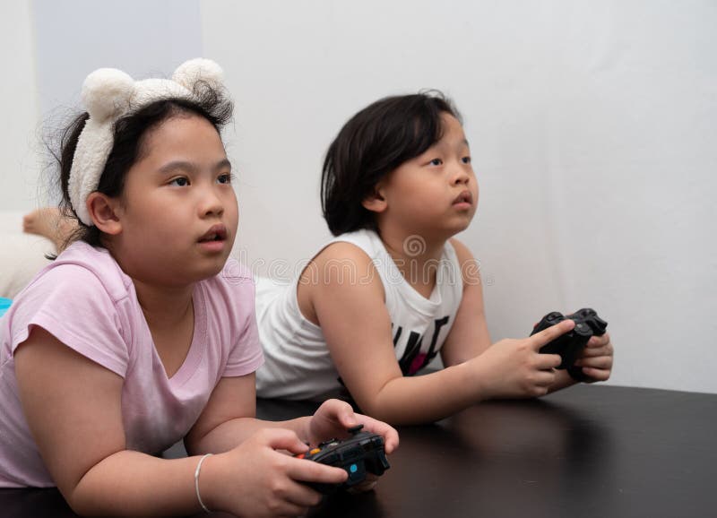 Asiatiska barn spelar videospel av styrenhet i hemmet arkivfoto
