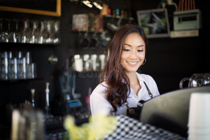Asiatiska kvinnor Barista som ler och använder kaffemaskinen i kaffe s arkivbilder Asiatiska kvinnor Barista som ler och använder kaffemaskinen i kaffe s arkivbilder