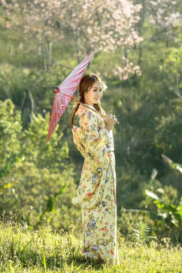 Asiatiska kvinnor som bär den traditionella japanska kimonot och det röda paraplyet arkivfoton Asiatiska kvinnor som bär den traditionella japanska kimonot och det röda paraplyet arkivfoton