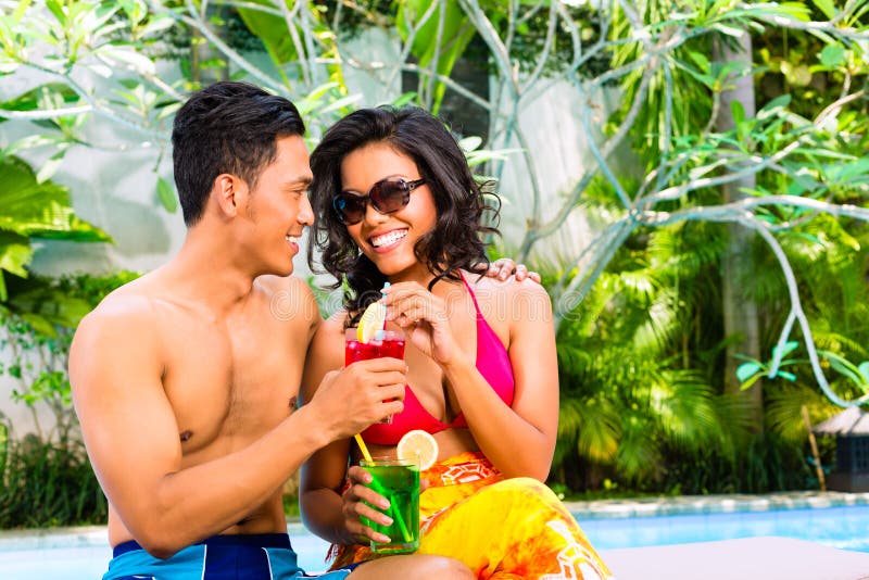 Asiatiska par som dricker coctailar på pölen royaltyfri fotografi Asiatiska par som dricker coctailar på pölen royaltyfri fotografi