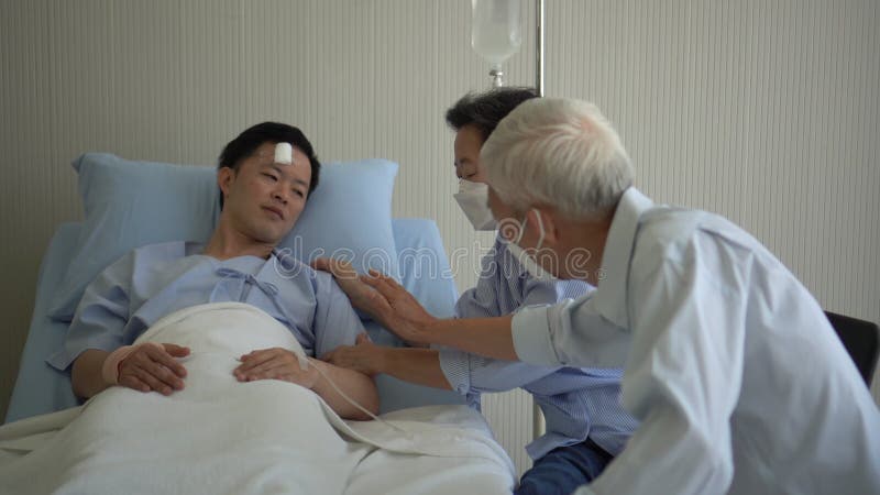 Asiatiska äldre föräldrar besöker vuxen son, gör barnskada i sjukhussängen 4k stock video