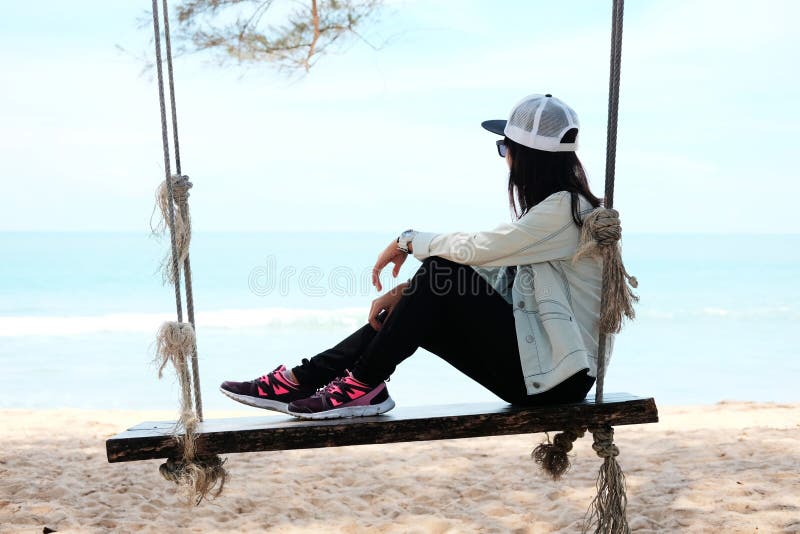 Asien-Frau, die allein auf Holzstuhlseil auf dem Strand schaut t sitzt
