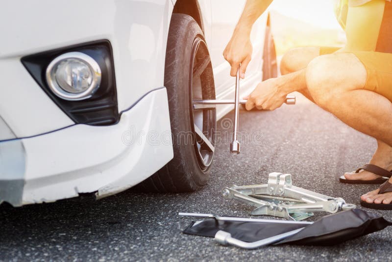Asien-Mann mit einem weißen Auto, das auf der Straße aufgliederte Ändernder Reifen auf defektem Auto stockbilder Asien-Mann mit einem weißen Auto, das auf der Straße aufgliederte Ändernder Reifen auf defektem Auto stockbilder
