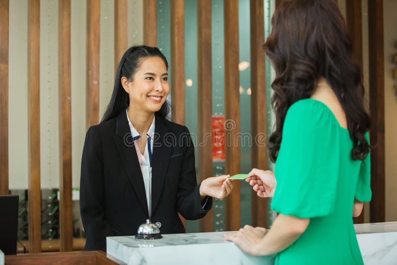 Asian woman reception hotel make registration of women guest`s stay, counter check in service customer, front lobby. Asian woman reception hotel make registration of women guest`s stay, counter check in service customer, front lobby.