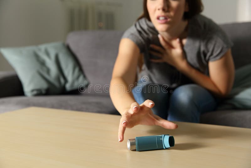 Asmathic flicka som fångar inhalatorn ha en astmaattack