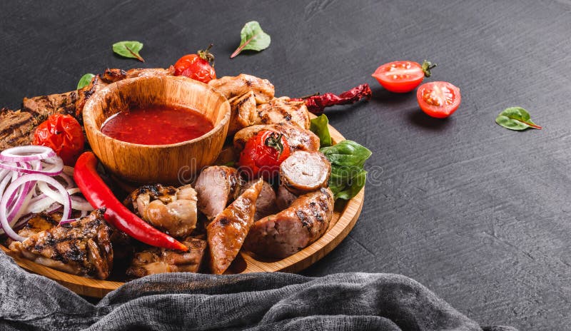 Asortowany wy?mienicie piec na grillu mi?so i kie?basy z pomidorami i bbq kumberlandem na tn?cej desce nad czerni? drylujemy t?o zdjęcie stock Asortowany wy?mienicie piec na grillu mi?so i kie?basy z pomidorami i bbq kumberlandem na tn?cej desce nad czerni? drylujemy t?o zdjęcie stock