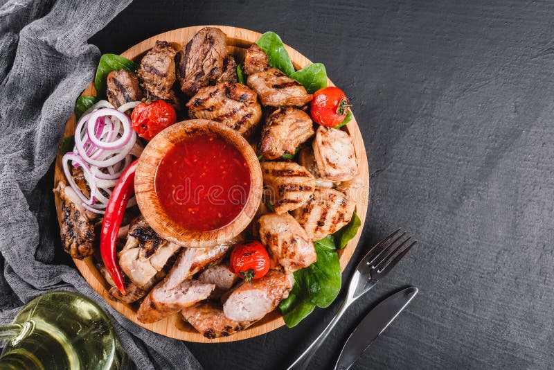 Asortowany wy?mienicie piec na grillu mi?so i kie?basy z pomidorami i bbq kumberlandem na tn?cej desce nad czerni? drylujemy t?o zdjęcia stock Asortowany wy?mienicie piec na grillu mi?so i kie?basy z pomidorami i bbq kumberlandem na tn?cej desce nad czerni? drylujemy t?o zdjęcia stock