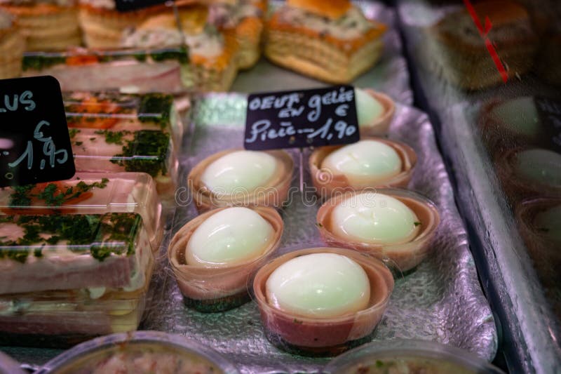 Assortment of meat on weekly food market in France, English translation: chicken eggs in jelly price of 1 piece. Assortment of meat on weekly food market in France, English translation: chicken eggs in jelly price of 1 piece