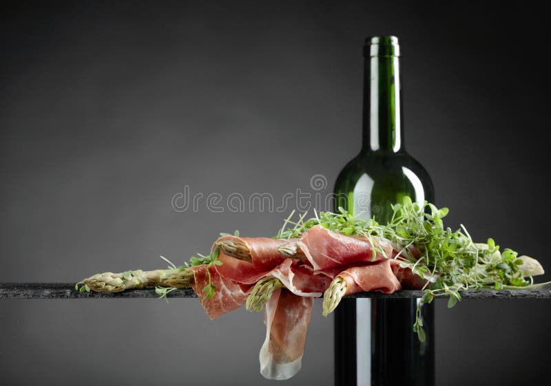 Asparago avvolto in prosciutto di Parma con vino rosso immagine stock Asparago avvolto in prosciutto di Parma con vino rosso immagine stock