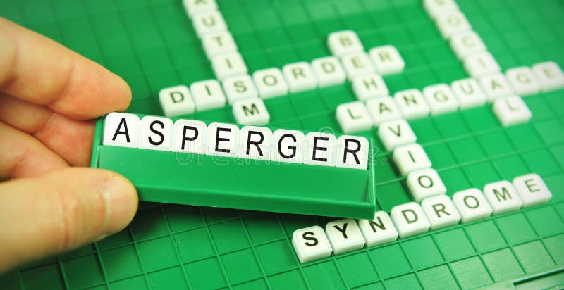 Ruka ukazující slovo Aspergerovým (autismus) na herní deska s klíčovými slovy.