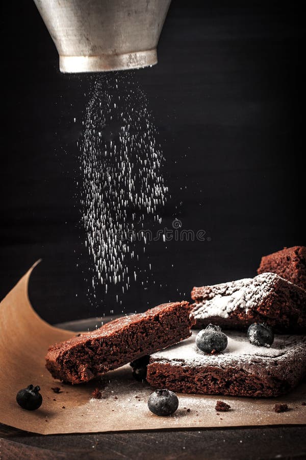 Aspersión del brownie del chocolate con el azúcar de formación de hielo y bluberry fotografía de archivo Aspersión del brownie del chocolate con el azúcar de formación de hielo y bluberry fotografía de archivo