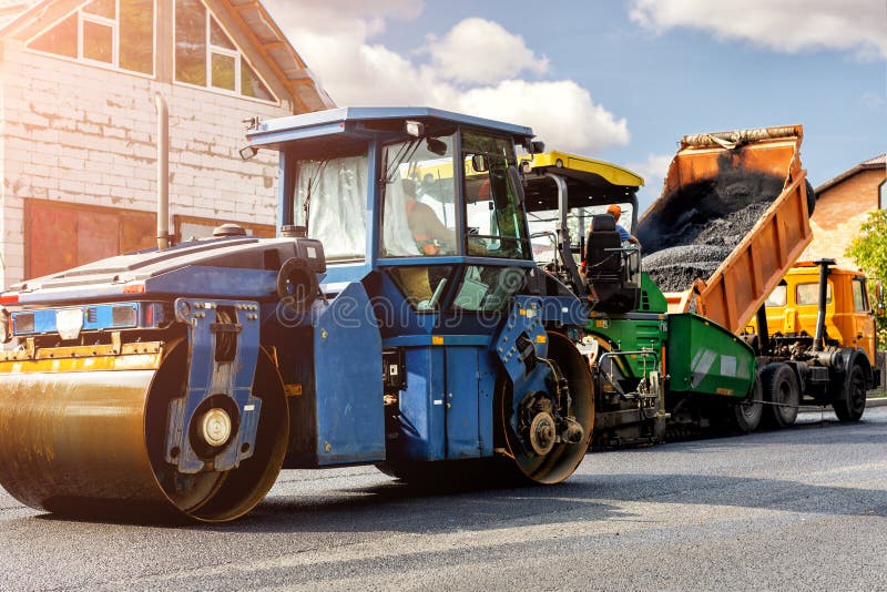 Asphalt higway road construction site. Heavy industrial machinery at roadworks and blue sky backround. Steam roadroller , paver