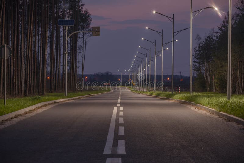 Asphalt road in the evening light, illuminated with the light of street lanterns.