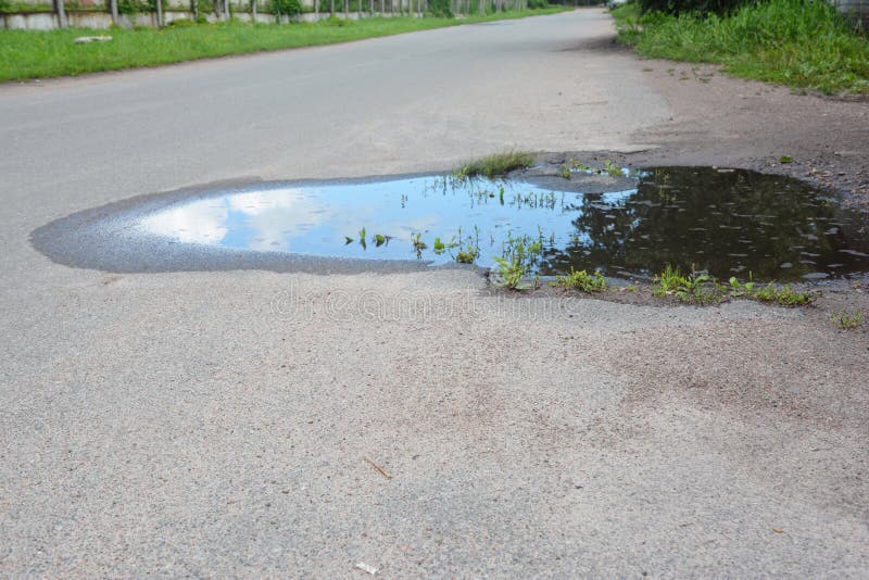 Asphalt road on puddles. Pot hole or pothole image of a broken cracked asphalt pavement royalty free stock photos Asphalt road on puddles. Pot hole or pothole image of a broken cracked asphalt pavement royalty free stock photos