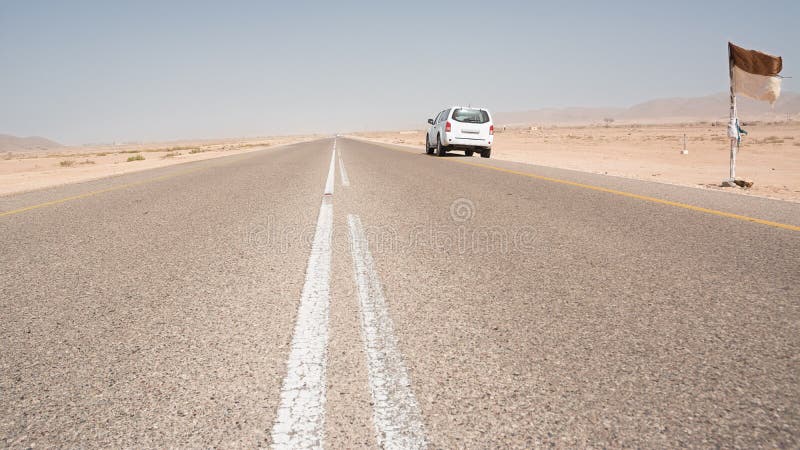 Asphalt road straight in the desert in the south of Oman with a parked 4x4 vehicle stock photos Asphalt road straight in the desert in the south of Oman with a parked 4x4 vehicle stock photos