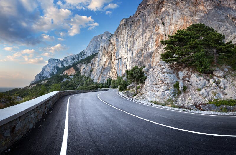 Asphalt road in summer forest at sunset. Crimean mountains