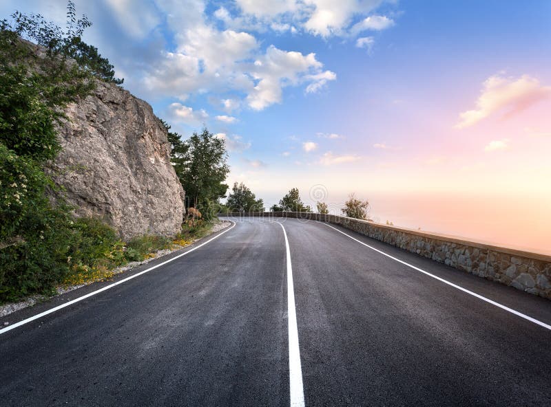 Asphalt road in summer forest at sunset. Crimean mountains