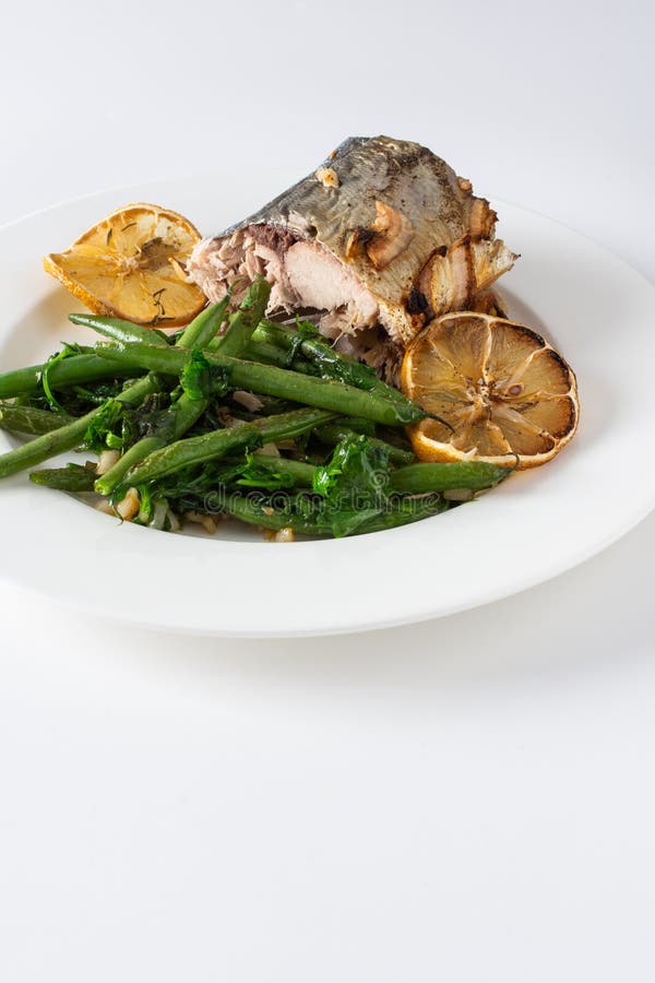 Assaporare i sapori sani di fagioli verdi al forno con cipolle e sgombro arrotolato elegantemente su fondo bianco fotografia stock libera da diritti