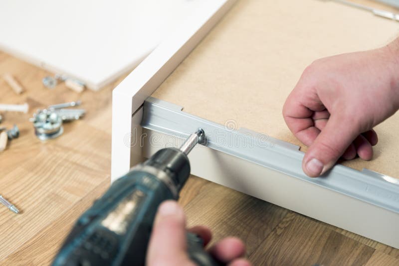 Assemblerend meubilair van spaanplaat, die draadloze screwdrive gebruiken stock afbeelding Assemblerend meubilair van spaanplaat, die draadloze screwdrive gebruiken stock afbeelding