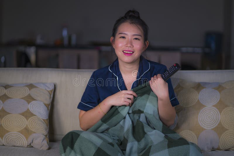 Assento chinês asiático feliz e relaxado bonito novo da sala de visitas da mulher em casa acolhedor no episódio de observação do imagens de stock royalty free Assento chinês asiático feliz e relaxado bonito novo da sala de visitas da mulher em casa acolhedor no episódio de observação do imagens de stock royalty free