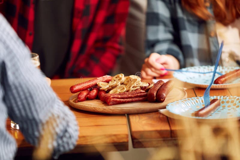 Wooden plate with many tasty sausages and pretzels on table with foamy lager beer glasses. Appetizers for alcohol drink. Concept of oktoberfest, traditional taste, friendship, leisure time, enjoyment. Wooden plate with many tasty sausages and pretzels on table with foamy lager beer glasses. Appetizers for alcohol drink. Concept of oktoberfest, traditional taste, friendship, leisure time, enjoyment